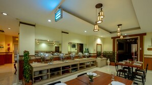 A spacious dining area with multiple tables, overhead lighting, and a long buffet counter. - Red Chilies Hotel (Surakarta)