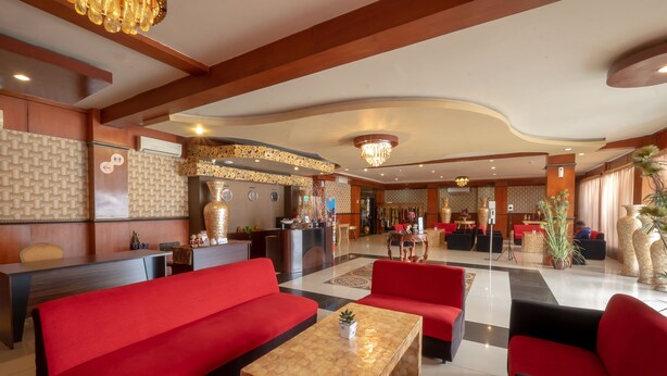 A hotel lobby with red sofas, a reception desk, and a large chandelier. - Red Chilies Hotel (Surakarta)