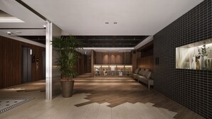 Un hall d’entrée moderne avec un plancher en bois, une grande plante en pot, un canapé et un écran fixé au mur.