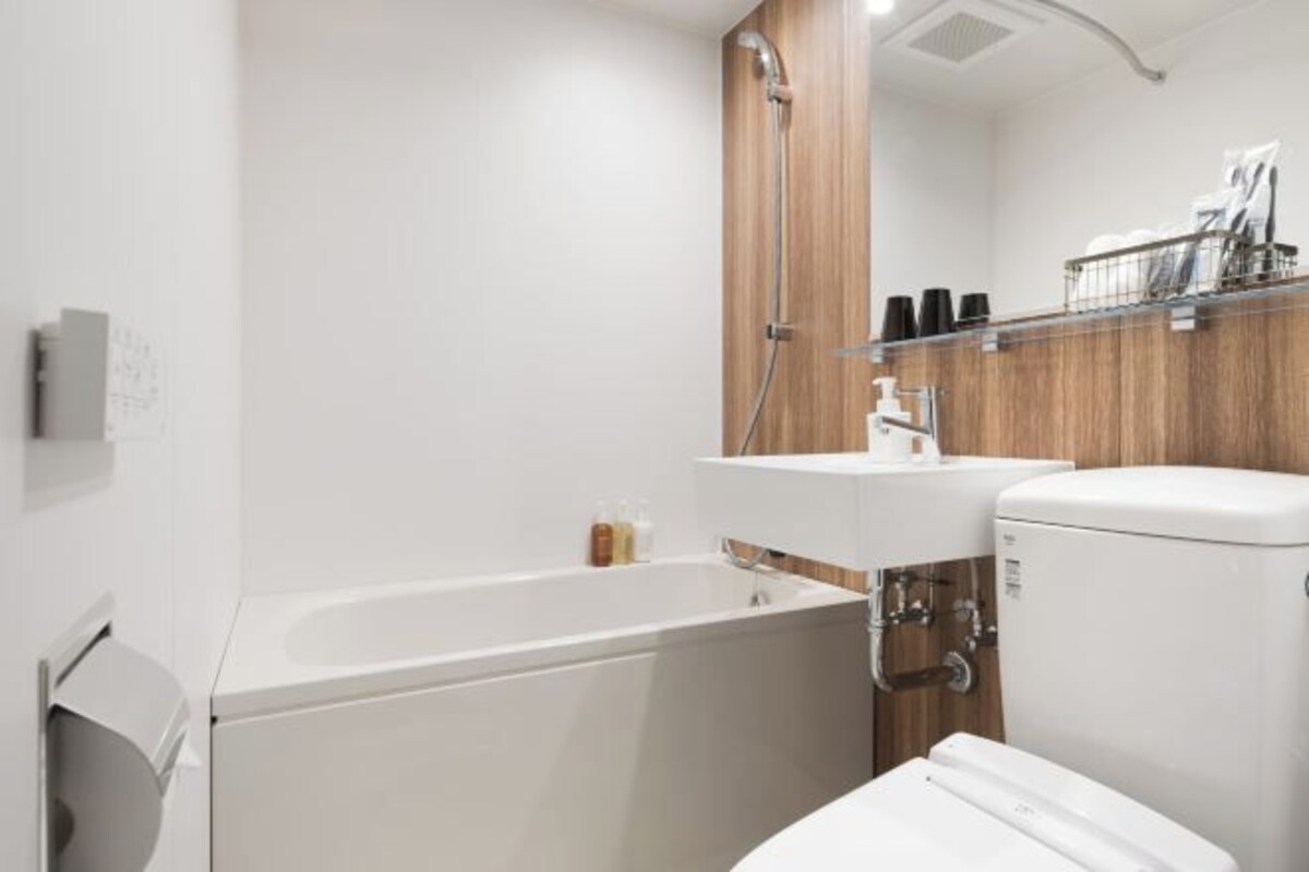 A modern bathroom with a white bathtub, a wooden vanity, and a toilet.