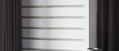 Un rincón de una habitación con una mesa de madera, un banco azul, una lámpara fijada a la pared y un objeto colgante.