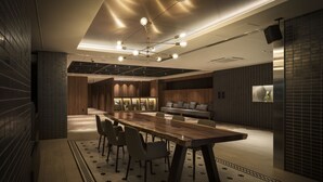 Un espace de restauration moderne avec une longue table en bois, des chaises et un luminaire central.