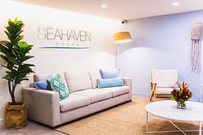 A modern living room with a sofa, a coffee table, a lamp, and a wall-mounted sign reading "SEAHAVEN". - Seahaven Noosa Beachfront Resort (Noosa Heads)
