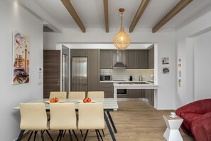 Une cuisine moderne avec des meubles gris, un réfrigérateur en acier inoxydable et un luminaire suspendu.