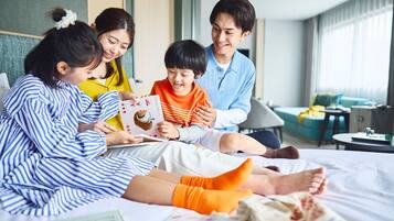 Una familia de cuatro personas en una habitación de hotel moderna con una cama, un sofá y una pequeña mesa.