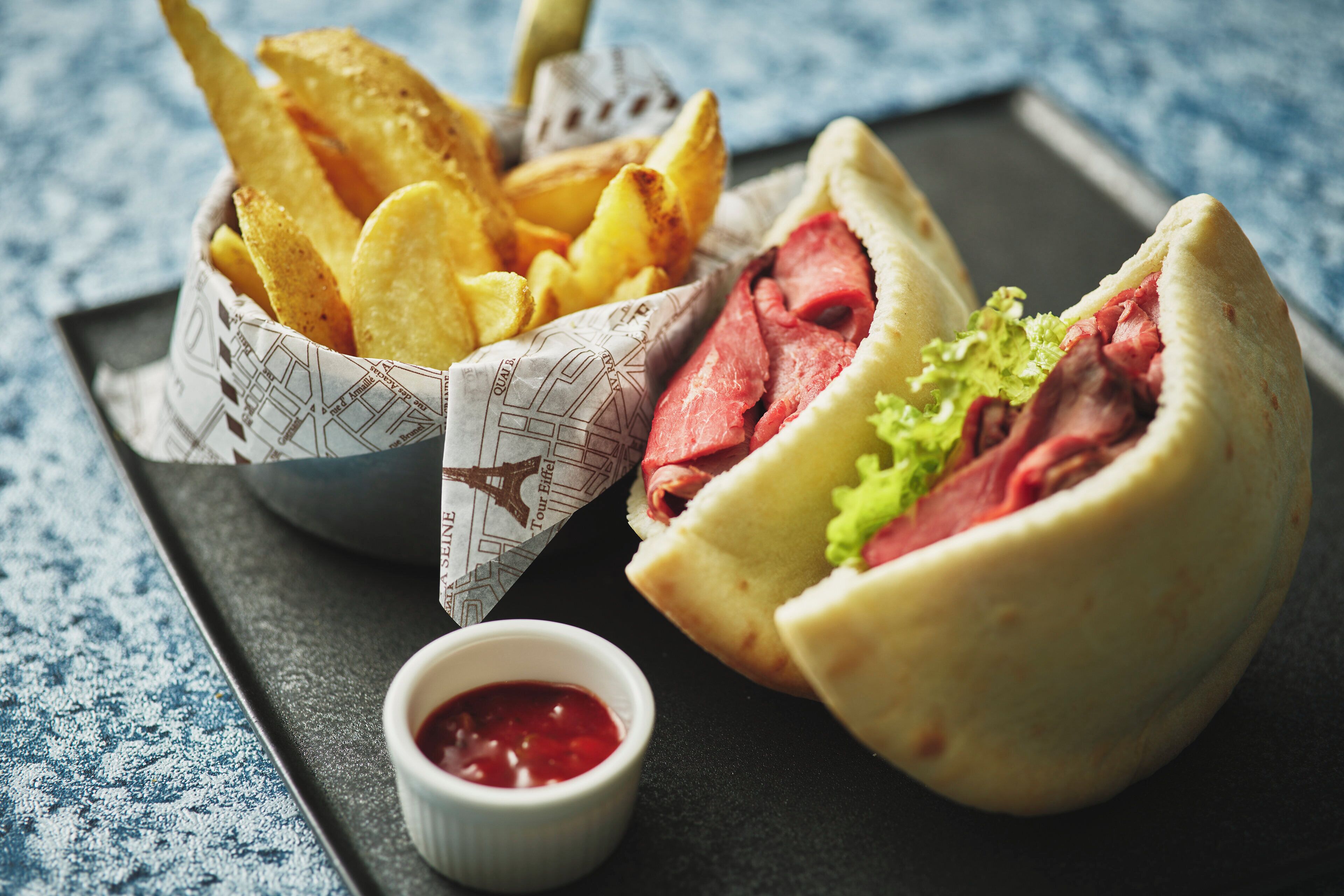Ein Hotdog mit Brötchen, Kartoffelchips und einer kleinen Schale Ketchup.