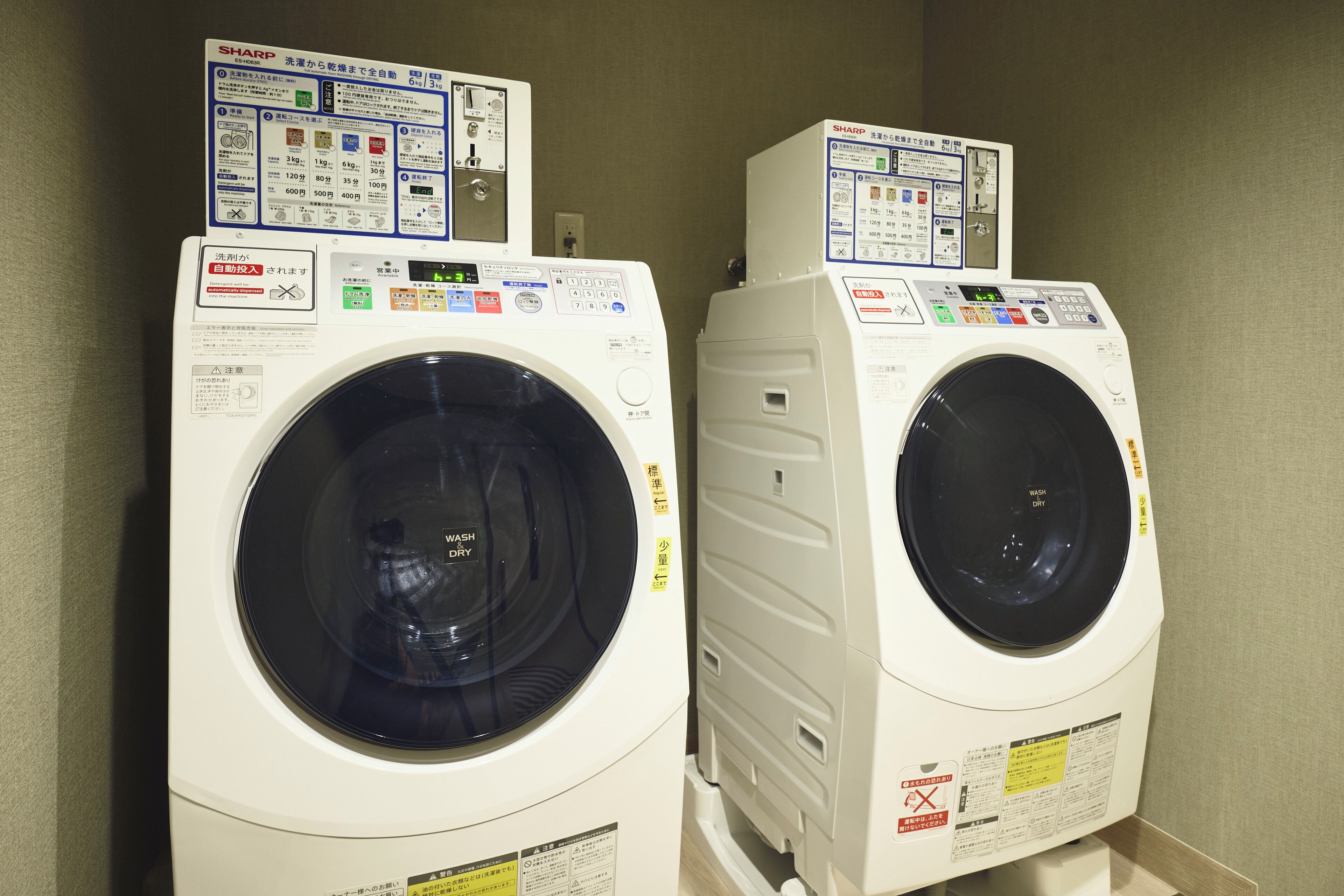 Two front-loading washing machines with control panels and instruction manuals.