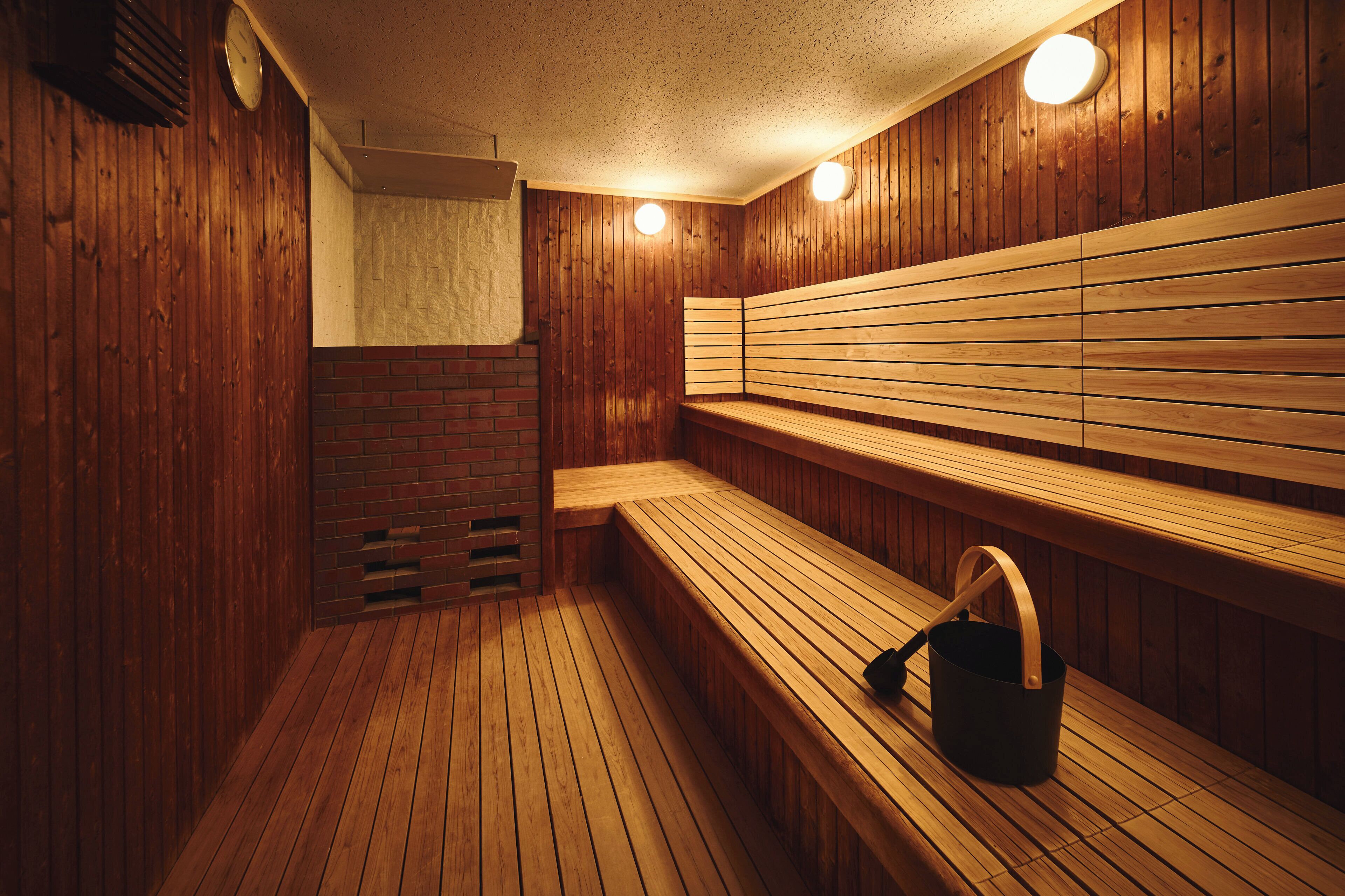 A sauna with wooden benches and a brick wall.