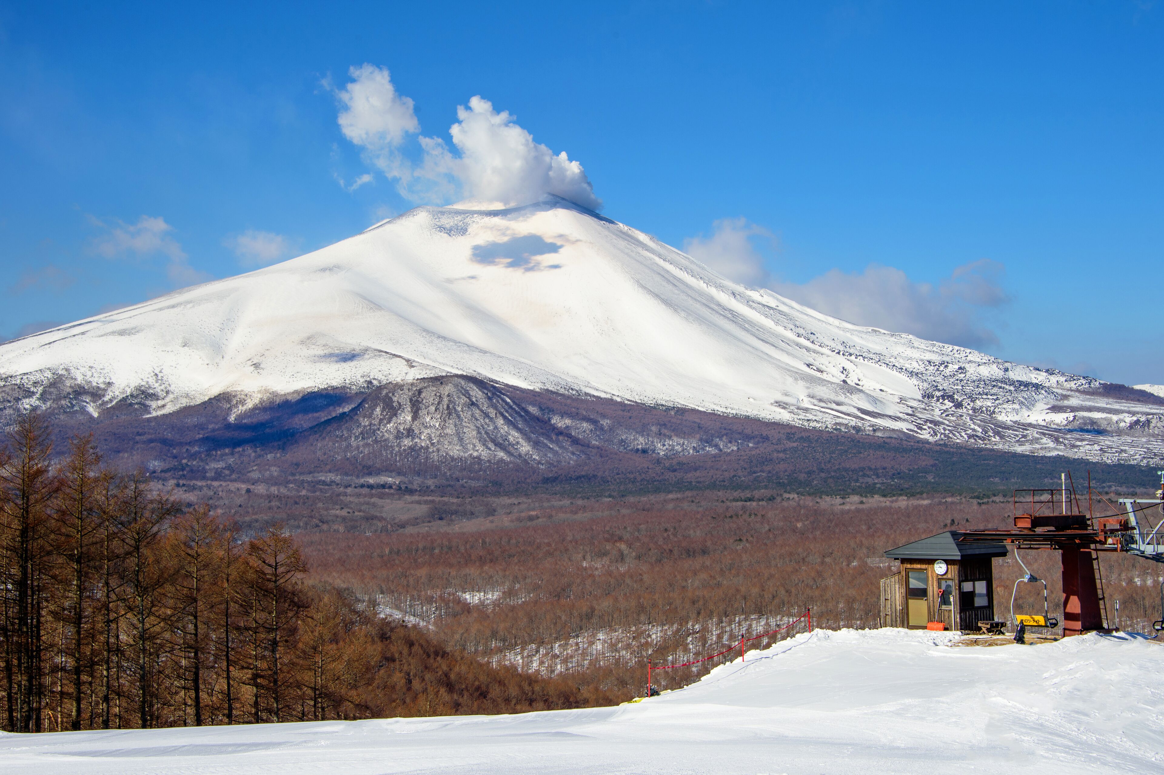 Une montagne enneigée, avec un petit chalet à son pied.