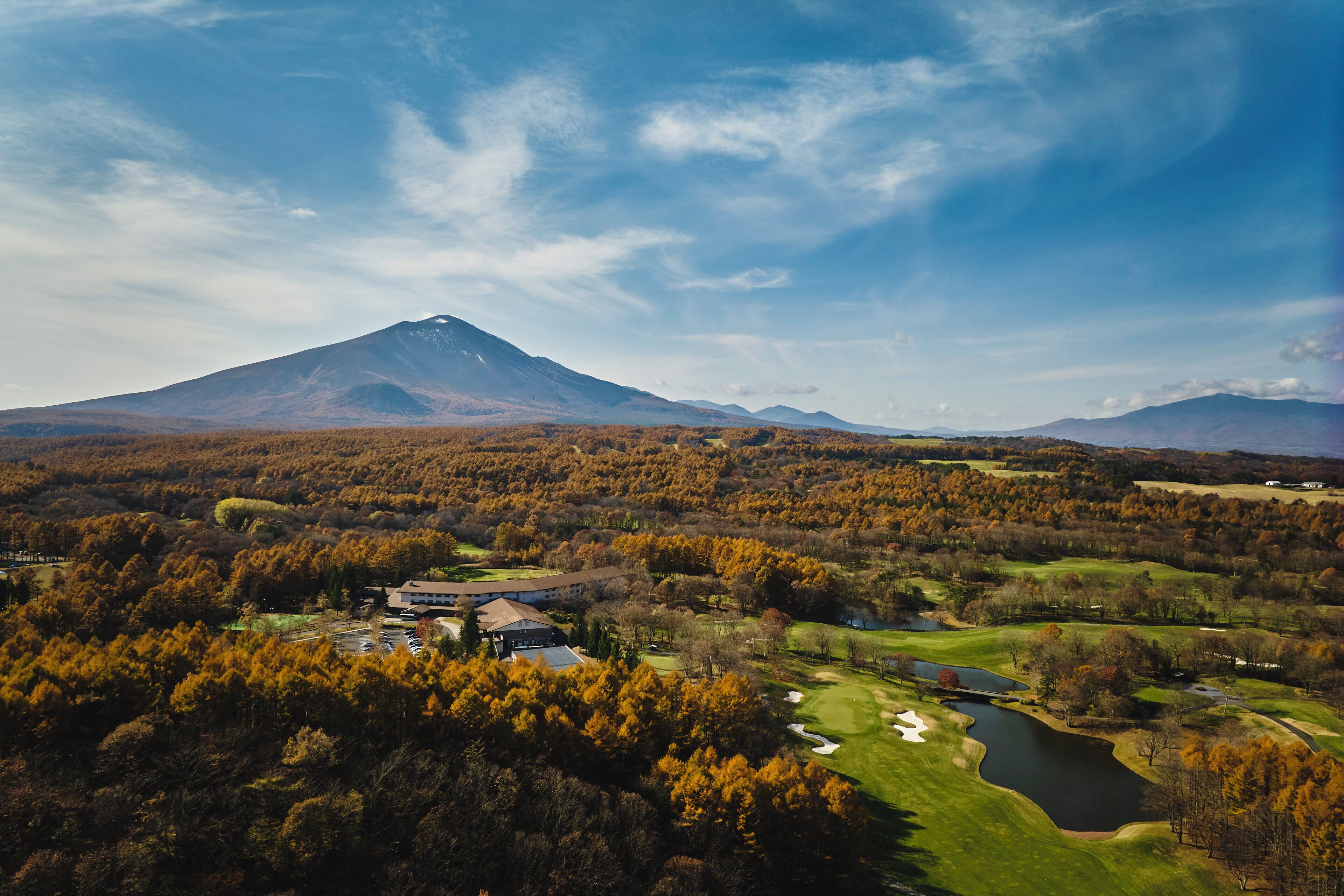 A mountain with a golf course in the foreground and a building in the middle ground.