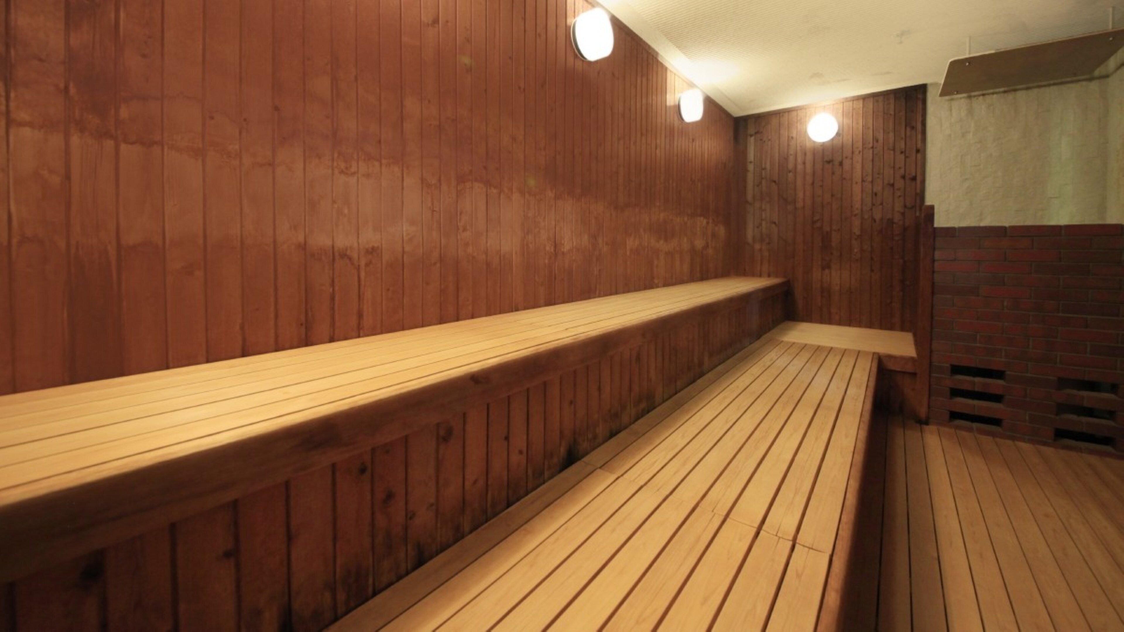 A wooden sauna with benches and a sloped floor.