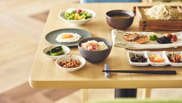 Una mesa de madera con varios platos, entre ellos arroz, verduras y pescado, dispuesta para una comida.