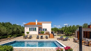 A modern house with a swimming pool, outdoor seating, and a stone wall. - An oasis of tranquility Villa Divinus, with heated pool (Polača)