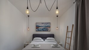 A neatly made bed with white linens and two rolled towels, a painting of a mountainous landscape on the wall, and a ladder leaning against the wall. - An oasis of tranquility Villa Divinus, with heated pool (Polača)