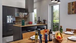 A modern kitchen with dark cabinets, a central island, and a dining area with wooden furniture. - An oasis of tranquility Villa Divinus, with heated pool (Polača)