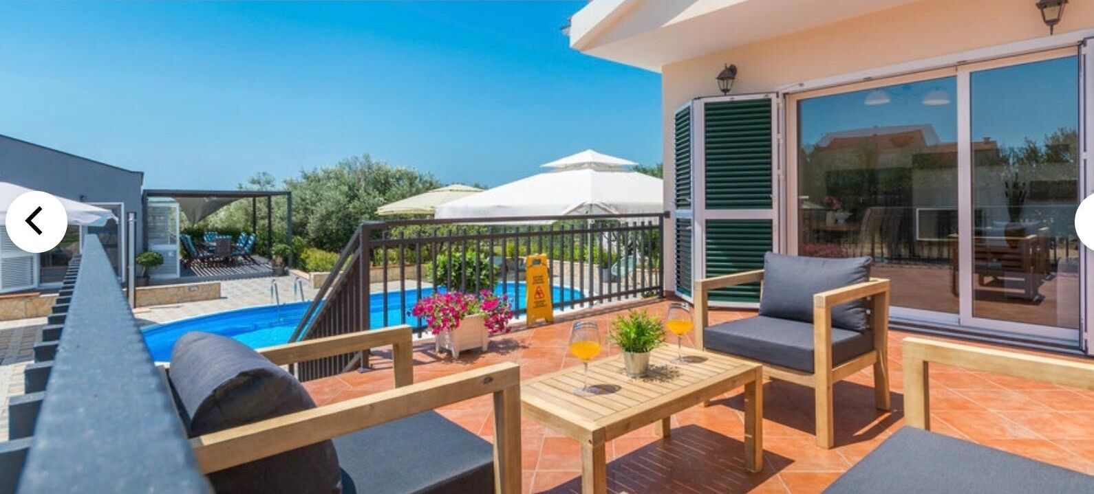 A balcony with a pool, outdoor seating, and a sliding glass door to a living area.