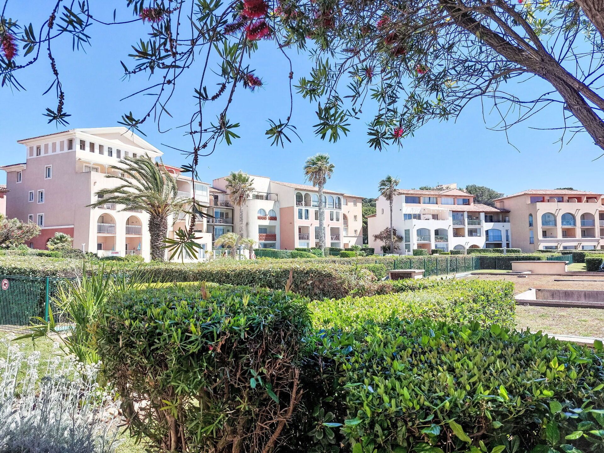 A hotel with multiple buildings, each featuring balconies and a Mediterranean architectural style.