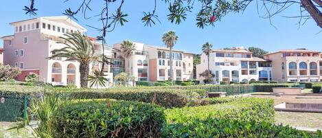 A hotel with multiple buildings, each featuring balconies and a Mediterranean architectural style.