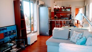 Un salon moderne avec un canapé, un téléviseur et une bibliothèque.