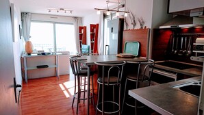 Une cuisine moderne avec un coin repas, un plancher en bois et une grande fenêtre.