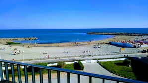 Une plage avec des gens, une jetée et une clôture.