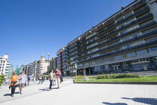 Zona peatonal con un edificio grande que presenta varios balcones y una torre central.