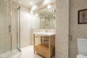 Un baño moderno con cabina de ducha de vidrio, un lavabo con espejo y un inodoro.