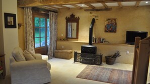 Una sala de estar acogedora con un sofá, una chimenea, un televisor y un amplio ventanal con cortinas.