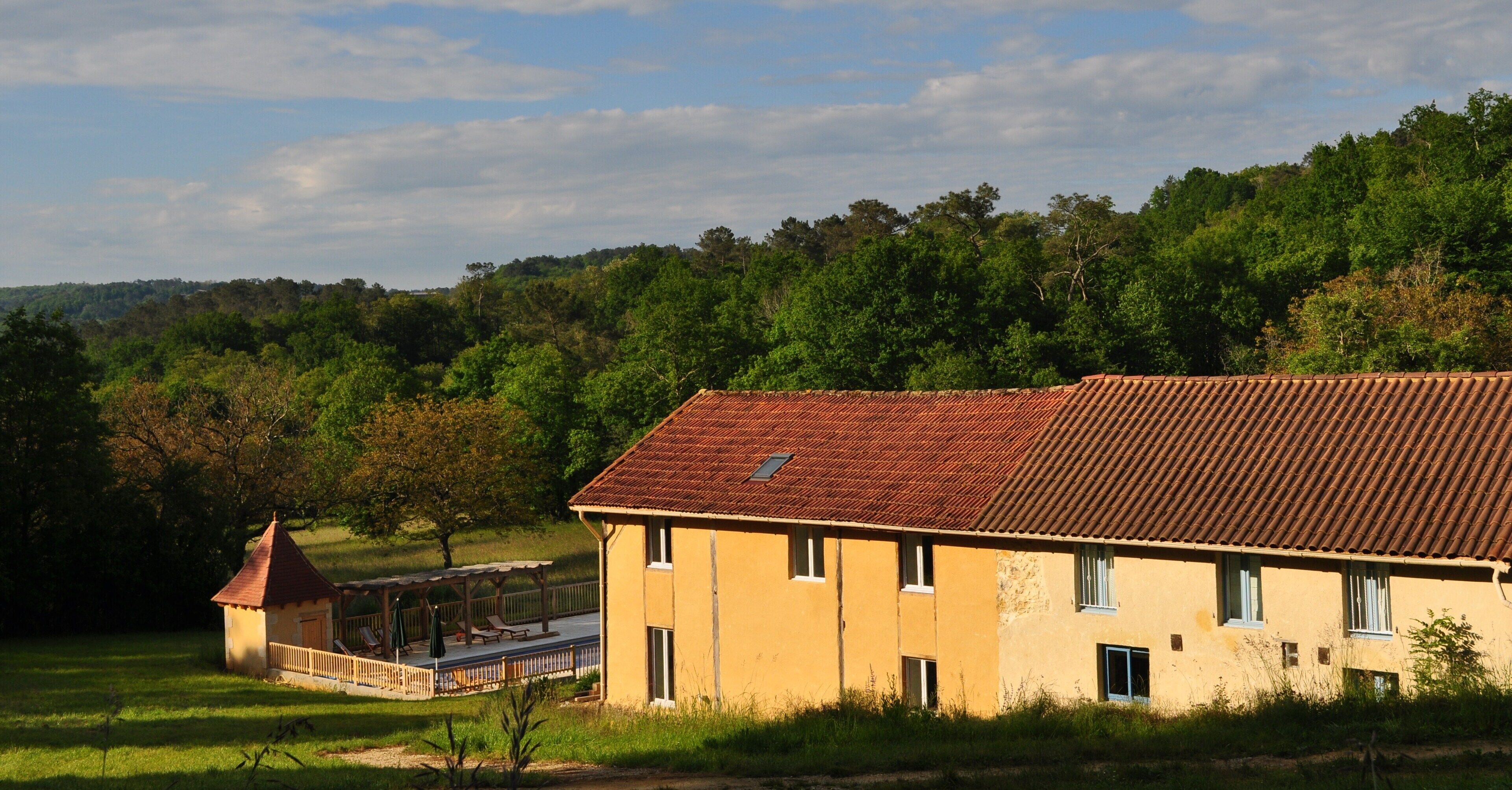 Un bâtiment jaune avec un toit rouge, une petite tour et un patio couvert.