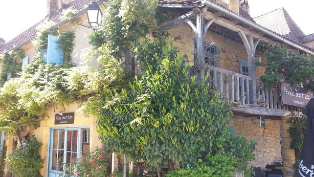 Un edificio rústico con un balcón, un letrero que dice 'Kenne de l'Isle Restaurant' y mesas al aire libre.