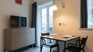 A modern kitchen with a dining table, chairs, a TV on a cabinet, and a window with curtains. - Vucciria suite behind the cathedral (Palermo)