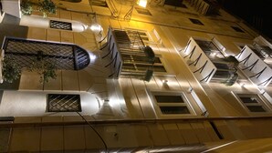 A nighttime view of a building with multiple balconies, a central column, and a series of windows. - Vucciria suite behind the cathedral (Palermo)