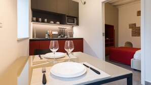 A modern kitchen with a microwave, cabinets, and a dining area with a table set for two. - Vucciria suite behind the cathedral (Palermo)