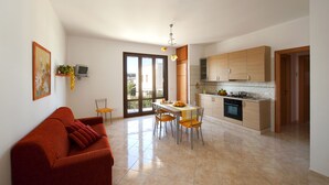 A modern kitchen with a dining area, a sofa, and a TV. - Brand new Rossoarancio apartment with panoramic terrace (San Vito Lo Capo)