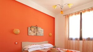 A bedroom with a bed, nightstand, and a painting on the wall. - Brand new Rossoarancio apartment with panoramic terrace (San Vito Lo Capo)