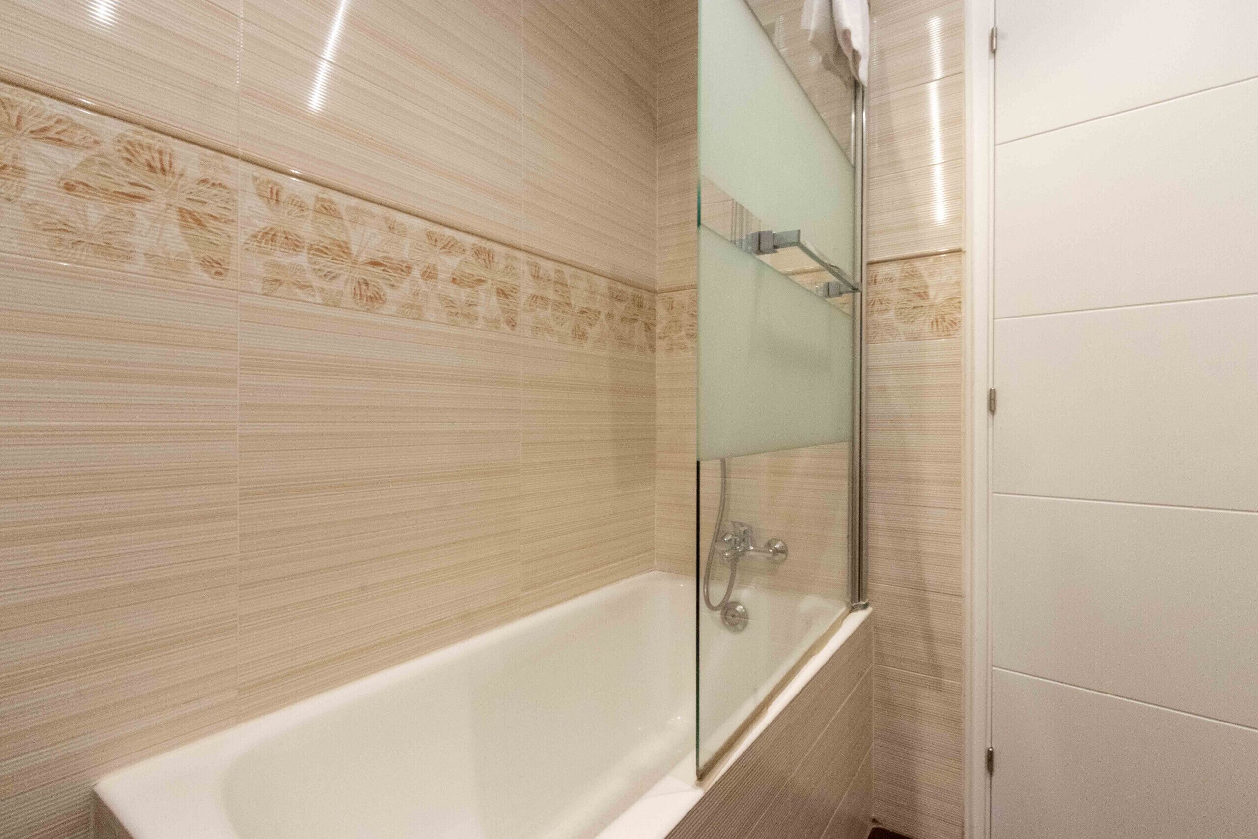 A modern bathroom with a freestanding bathtub, a glass shower enclosure, and patterned wall tiles.