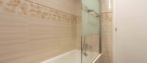 A modern bathroom with a freestanding bathtub, a glass shower enclosure, and patterned wall tiles.