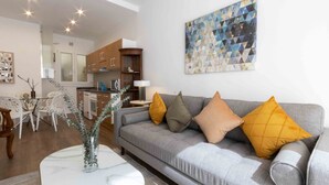 A modern living room with a grey sofa, yellow cushions, a marble coffee table, and a geometric painting on the wall. - Urbieta | The Rentals Collection (San Sebastián)