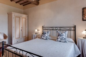 A bedroom with a bed, two bedside tables with lamps, a wardrobe, and a painting on the wall.