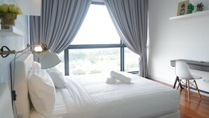 A modern bedroom with a large bed, grey curtains, a desk, and a chair. - Bora Residence (Johor Bahru)