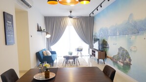 A modern living room with a dining table, blue sofa, and a scenic mural of a coastal landscape. - Bora Residence (Johor Bahru)