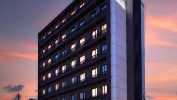 A multi-story hotel with a prominent sign on the corner, multiple windows on each floor, and a flat roof.