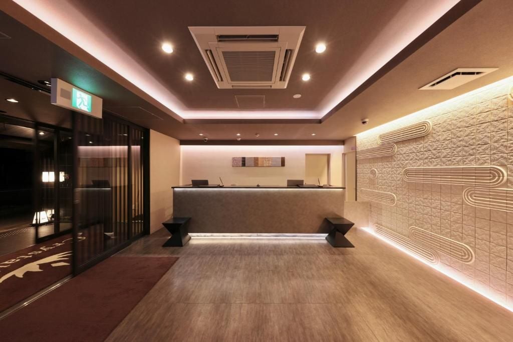Zona de recepción de un hotel con diseño moderno, que incluye un mostrador de recepción, un panel informativo en la pared y un diseño de pared estampado.