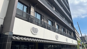 A multi-story building with a modern architectural design, featuring large windows and a prominent logo on the facade. - Hotel Japanesque Kyoto Station ZEQUU (Kyoto)