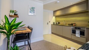 A modern kitchen with a wooden countertop, stainless steel appliances, and a small dining area with a table and chairs.