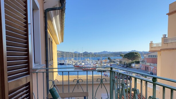 A balcony with a view of a marina, a champagne bucket, and two glasses.