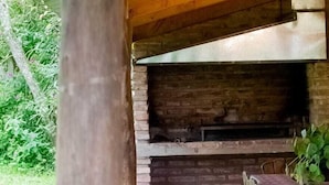 An outdoor patio with a brick fireplace, wooden table and chairs, and a concrete floor. - Allegra Casas de Campo (Vaqueros)