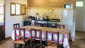 A rustic kitchen with a wooden ceiling, brick wall, and a dining table with chairs. - Allegra Casas de Campo (Vaqueros)