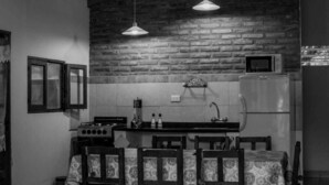 A rustic kitchen with a brick wall, a gas stove, a refrigerator, and hanging pendant lights. - Allegra Casas de Campo (Vaqueros)