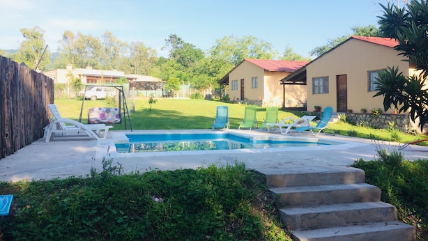 A backyard with a swimming pool, green lawn, and a house with a red roof. - Allegra Casas de Campo (Vaqueros)